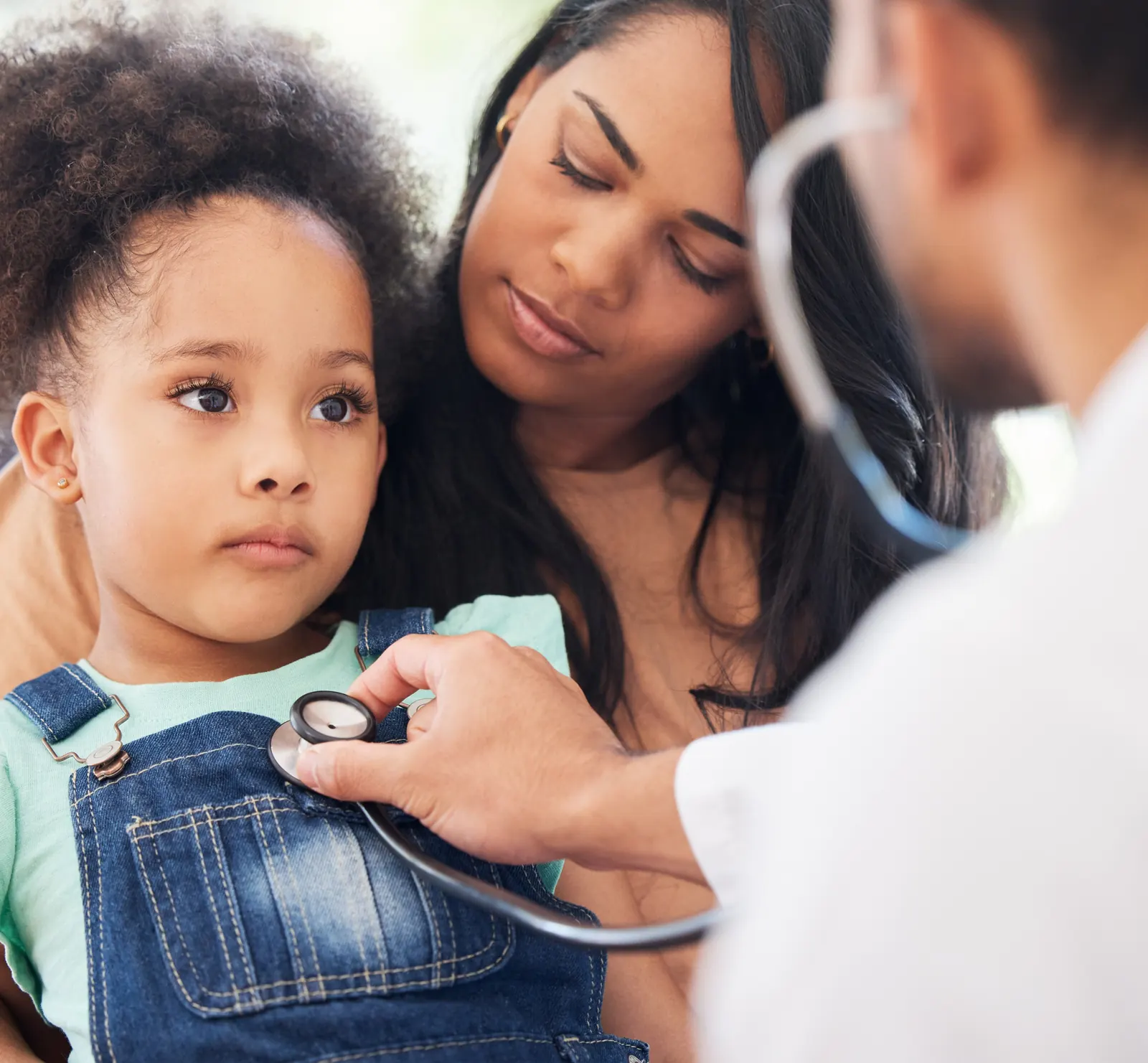 Pediatra examinando a una niña acompañada de su madre en un centro de salud